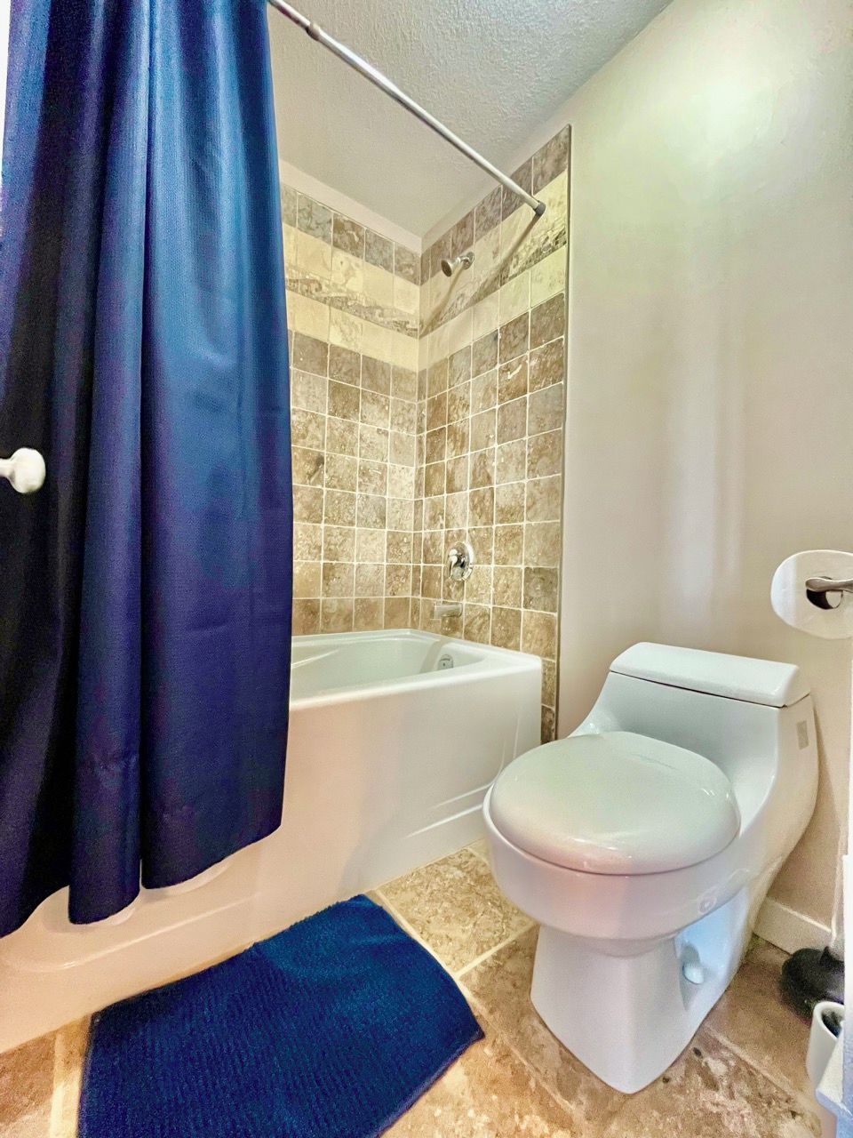 A bathroom with a bathtub, toilet, and shower curtain.