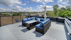 A rooftop deck with a sectional sofa, outdoor table, and umbrella.