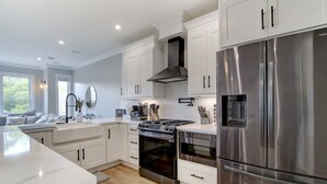 A modern kitchen with white cabinets, stainless steel appliances, and a large island.