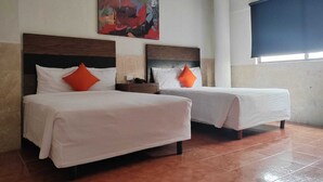 Habitación de hotel con dos camas, cada una con ropa de cama blanca y almohadas naranjas, una mesita de noche con un teléfono y un cuadro abstracto grande en la pared.