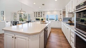 A spacious kitchen with white cabinetry, a large island, and a view through the window. - Mansion in La Jolla Heights-Pool, Spa, OceanViews (San Diego)