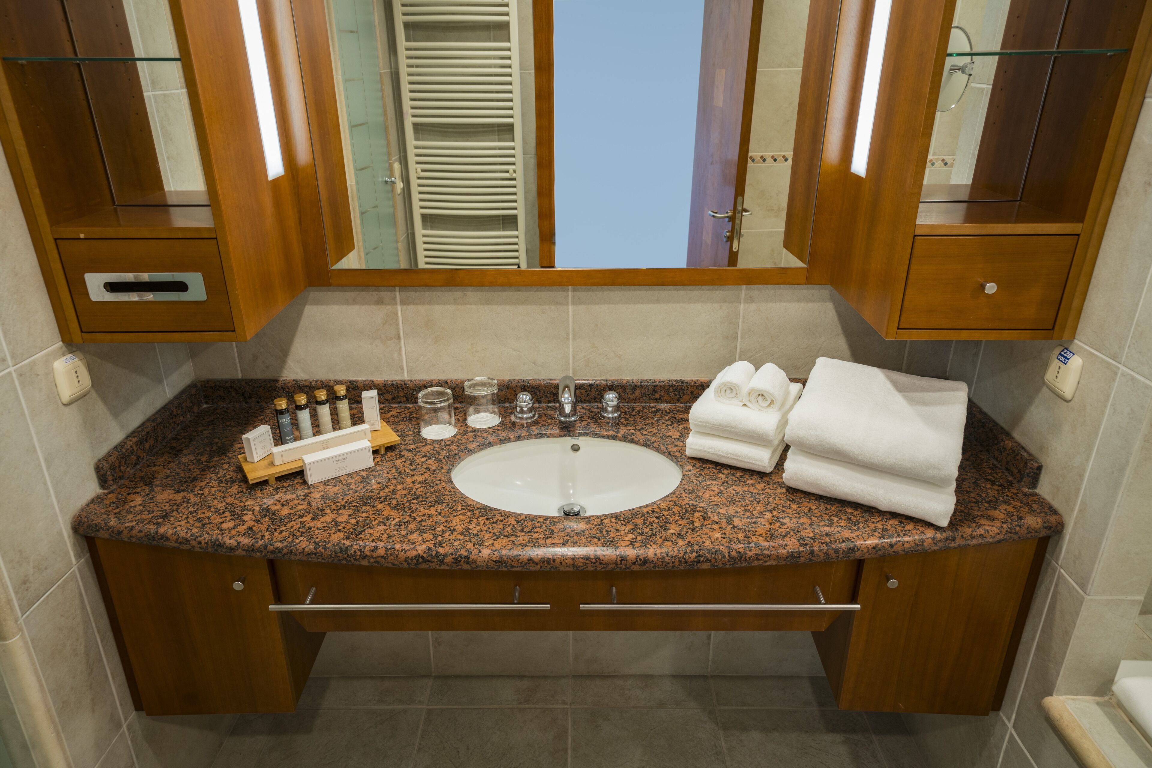 A bathroom with a granite countertop, a sink, and a mirror.