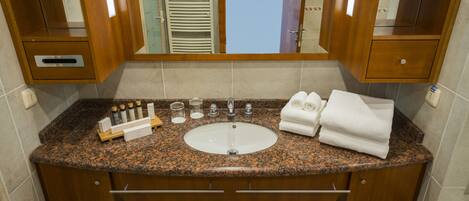 Un baño con encimera de granito, un lavabo y un espejo.