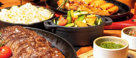 Variedad de platos que incluyen bistec, arroz y verduras en cazuelas de hierro fundido.