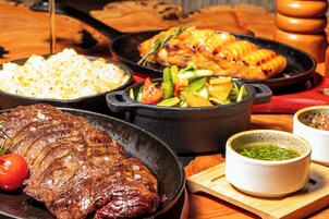 Variedad de platos que incluyen bistec, arroz y verduras en cazuelas de hierro fundido.
