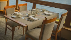 Un comedor con una mesa dispuesta para cuatro, amplias ventanas que ofrecen vistas al mar y a las montañas.