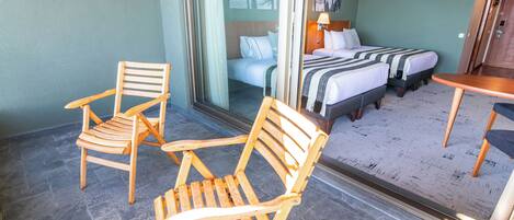 A hotel room with two wooden chairs, a bed with a striped blanket, and a small table.