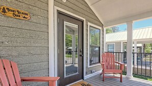 Una cabaña de madera con un porche, dos sillas Adirondack y un letrero que dice 'Beary Relaxing Cabin'.