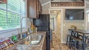 Una cocina con encimera de granito, pileta de acero inoxidable, muebles de madera y microondas integrado.