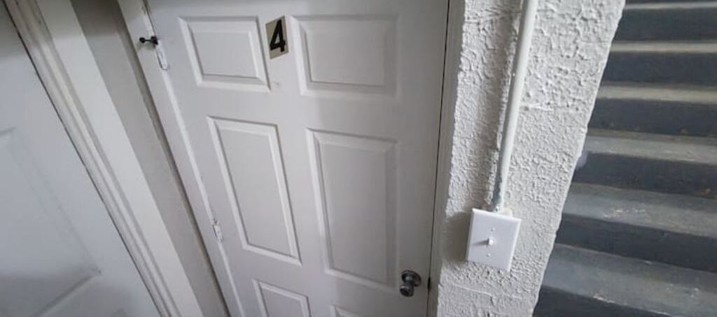 A white door with the number 4, a white wall, and a textured surface.