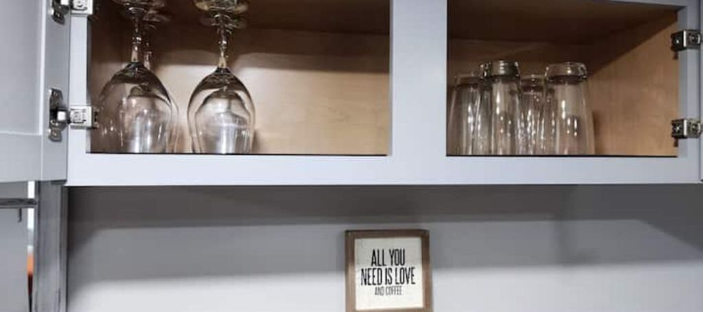 Un meuble de cuisine contenant des verres à vin et des bocaux.