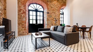 A living room with a stone wall, a sofa, a coffee table, and a dining area with chairs and a table. - Lefevre 1B (Panama City)