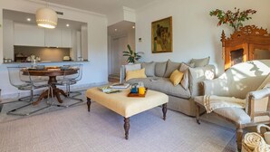 A modern living room with a sofa, a coffee table, and a dining area with a table and chairs. - Puerto Banús Cozy and Luxe Home (Marbella)