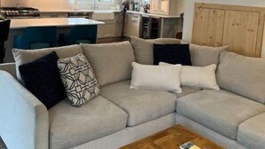 A modern living room with a sectional sofa, a coffee table, and a kitchen in the background. - Walk or bike to everything Lewes has to offer! (Lewes)