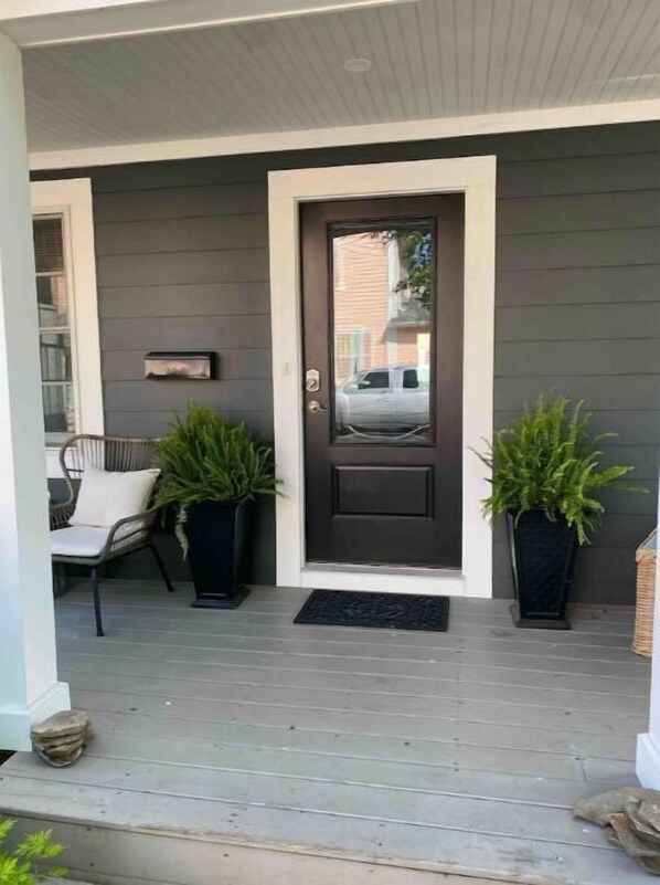 Welcome to a charming entrance with a cozy chair and lush greenery.