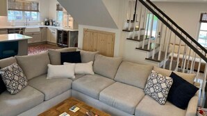 A modern living room with a sectional sofa, a coffee table, and a staircase leading to an upper level. - Walk or bike to everything Lewes has to offer! (Lewes)