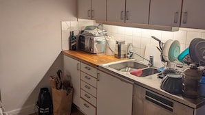 Una cucina compatta con mobili bianchi, un piano di lavoro in legno, un lavello e una lavastoviglie.