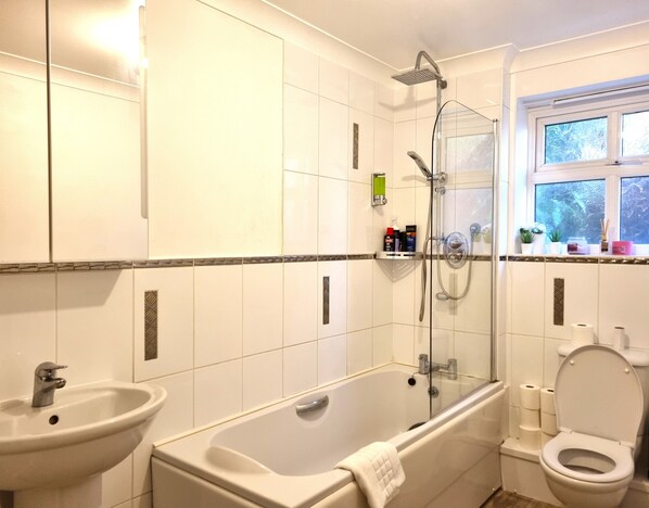 A bathroom with a bathtub, a sink, a toilet, and a window. - The Belmont Old Town (Swindon)
