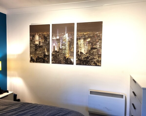 A bedroom with a cityscape artwork on the wall, a bed, a desk, and a radiator. - The Belmont Old Town (Swindon)