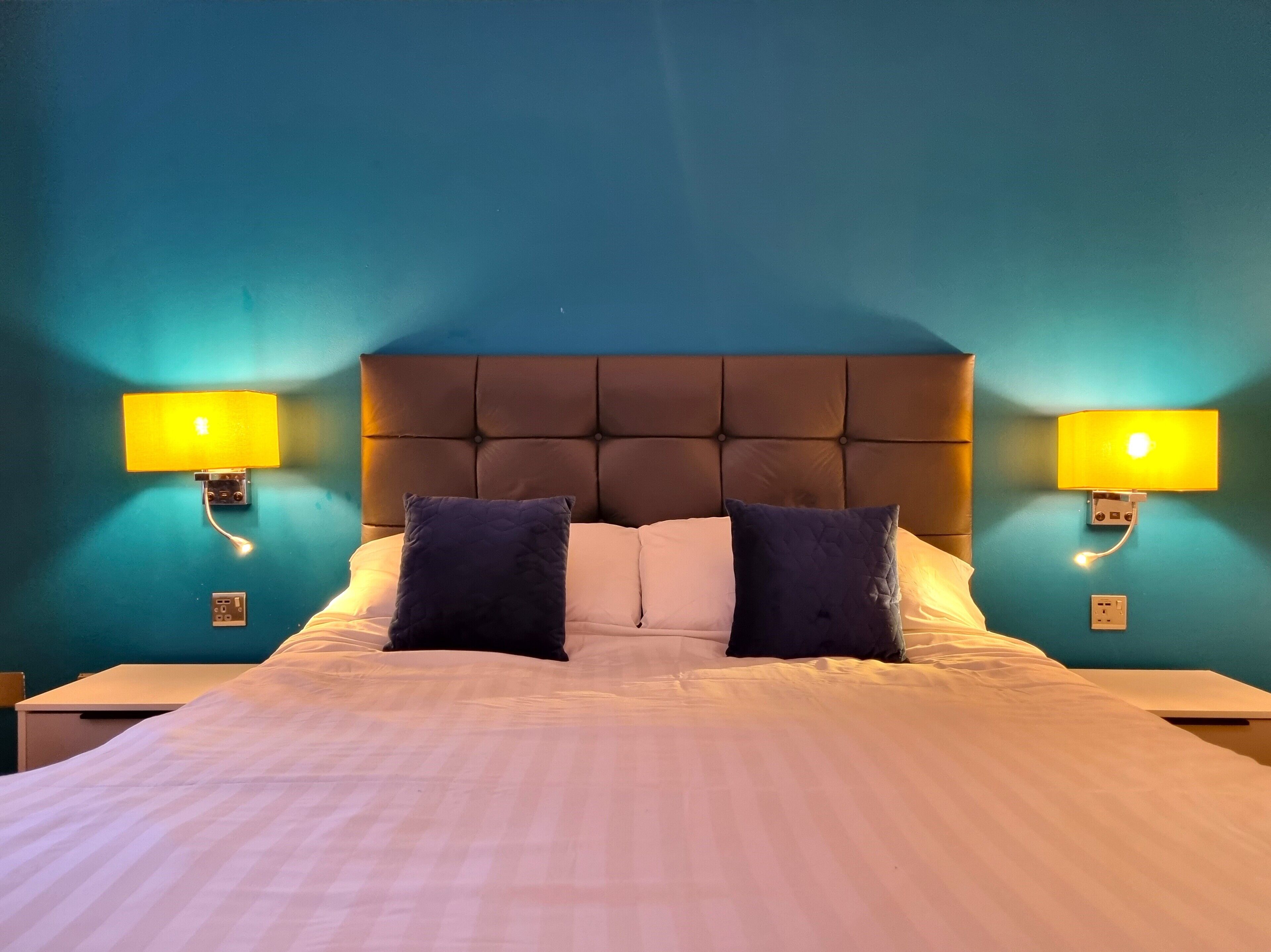 A bed with a tufted headboard, two bedside lamps, and two pillows.