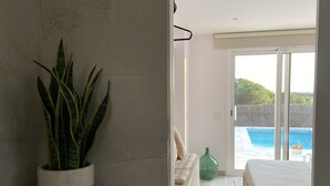 Une chambre d’hôtel moderne dotée d’une grande porte-fenêtre coulissante donnant accès à un espace piscine.