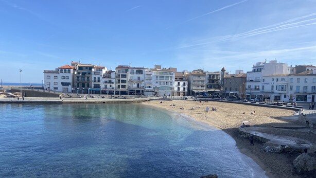 Une ville côtière dotée d’une plage de sable fin, de bâtiments avec des balcons et d’un littoral rocheux.