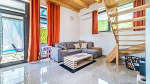 A modern living room with a grey sofa, a small coffee table, and a wooden staircase.