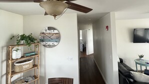 A living room with a ceiling fan, a wall clock, a bookshelf, a sofa, and a television.