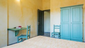 Een slaapkamer met een bed, twee stoelen, een bureau en een kledingkast.