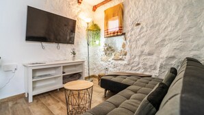 A cozy living room with a large flat-screen TV, a white entertainment unit, a round coffee table, and a grey sofa. - Cozy apartment in Ubrique with WiFi (Ubrique)