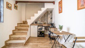 A staircase leading to a kitchen with a small refrigerator, a wooden table, and a bench. - Cozy apartment in Ubrique with WiFi (Ubrique)