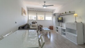 Een moderne woonkamer met een eettafel, bank, televisie en ingebouwde boekenkasten.