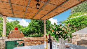 An outdoor patio with a table set for dining, a bottle of wine, and a vase of flowers. - 2 bedroom amazing home in Orebic (Orebic)
