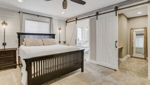 A bedroom with a bed, a ceiling fan, and a sliding door leading to a bathroom. - Staycation (Colorado Springs)