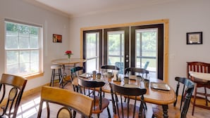 A dining area with wooden tables and chairs, large windows, and a view of greenery outside. - Waterfront Smith Mountain Lake Home w/ Boat Dock! (Goodview)