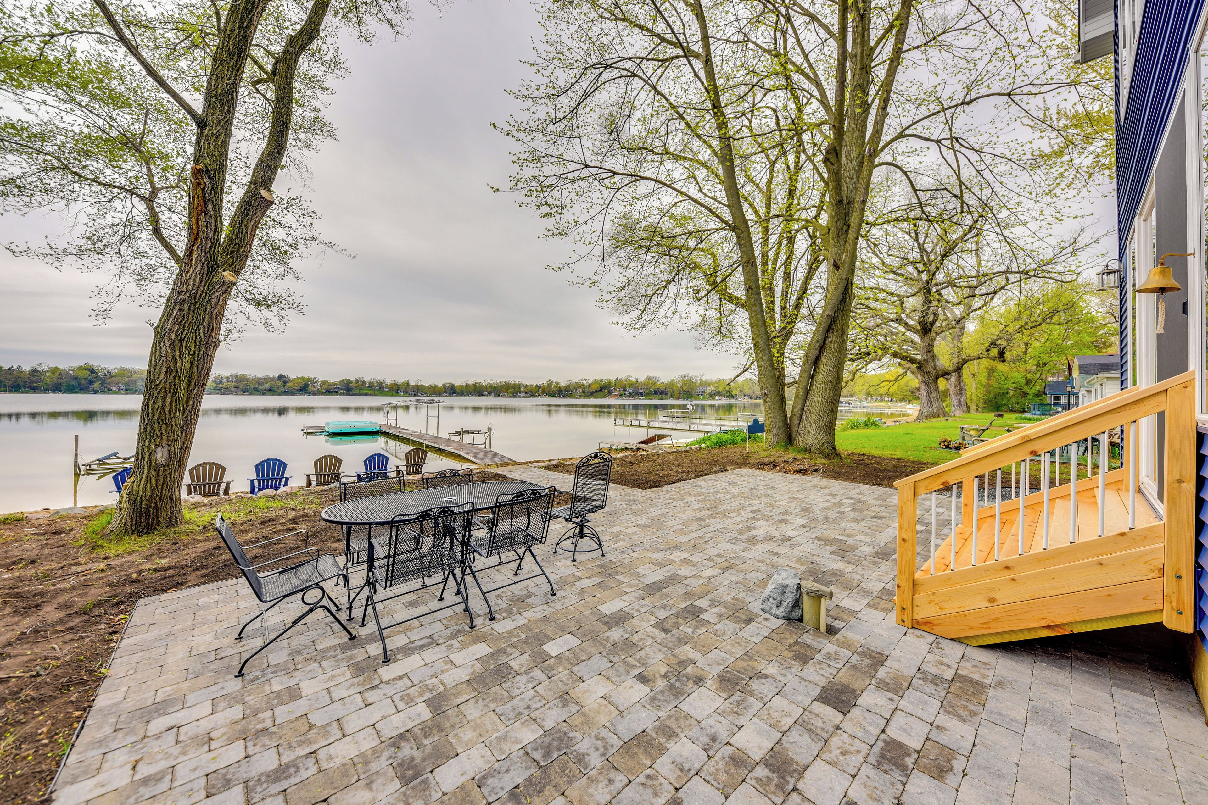 A patio with a table and chairs, a wooden staircase, and a view of a lake.
