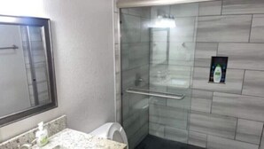 A bathroom with a glass-enclosed shower, a toilet, and a sink with a soap dispenser. - Stylish 2BD/2BA in Arlington | Convenient & Clean! (Arlington)