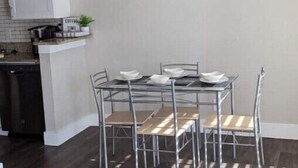 A modern kitchen with white cabinets, a built-in oven, and a dining area with a glass table and metal chairs. - Stylish 2BD/2BA in Arlington | Convenient & Clean! (Arlington)