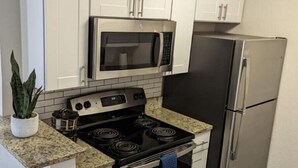 A kitchen with white cabinets, a black stove, a microwave, and a stainless steel refrigerator. - Stylish 2BD/2BA in Arlington | Convenient & Clean! (Arlington)