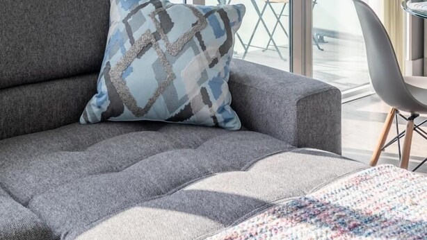 A modern hotel room with a grey sofa, a patterned throw pillow, and a view of the city through large glass doors. - GLOBALSTAY.  Design 26Floor Downtown Apartment (Toronto/Canada)