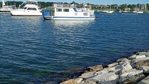 Un port de plaisance où sont amarrés plusieurs bateaux, une côte rocheuse et un ciel dégagé.