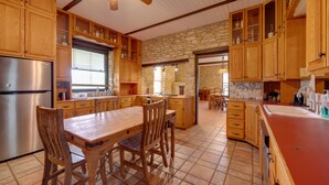Una cocina amplia con armarios de madera, una isla central y una pared de piedra.