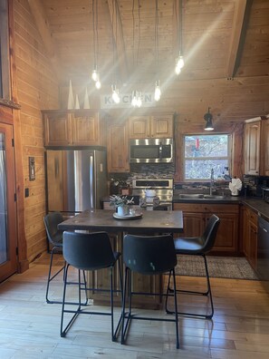 A wooden cabin-style kitchen with a dining table, chairs, and modern appliances.