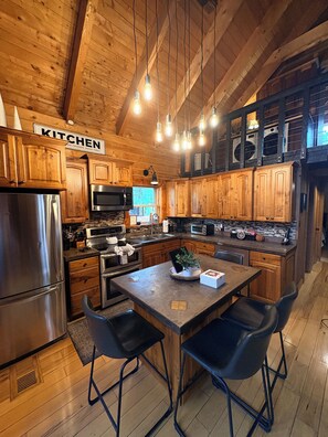 A kitchen with wooden cabinets, stainless steel appliances, and pendant lighting.