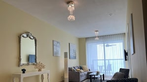 Uma sala de estar com sofá, poltronas, mesa de centro, aparador com espelho e um abajur de chão.