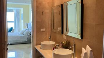A modern bathroom with two sinks, a mirror, and a towel rack.