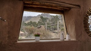 A rustic room with a window overlooking a mountainous landscape. - Andean Glamping (Pisac)