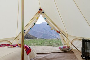 Una tienda de campaña con una cama, una pequeña mesa y vistas a las montañas.