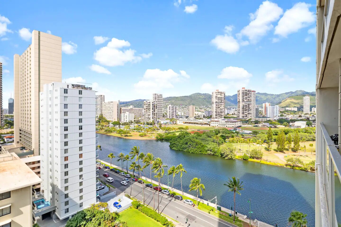 A high-rise hotel with a view of a river and surrounding greenery.