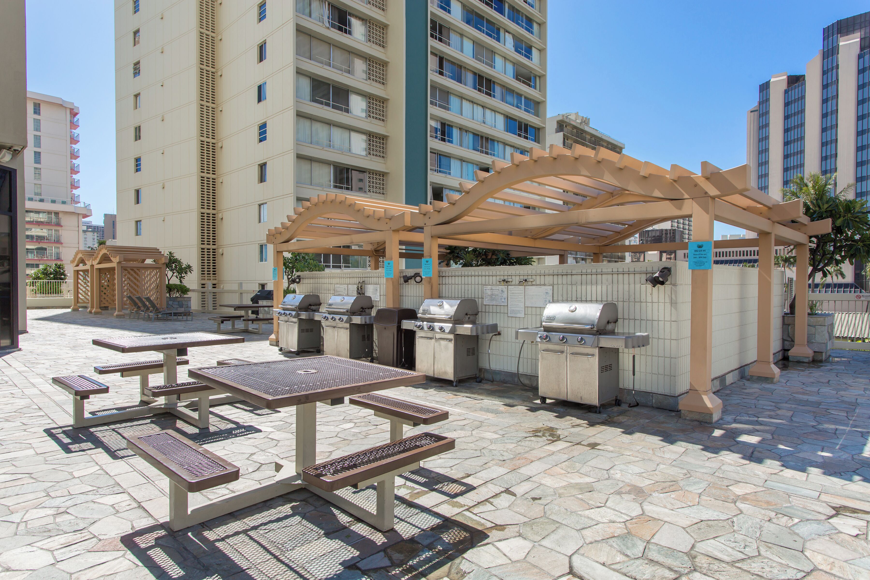 An outdoor patio with picnic tables and barbecue grills.